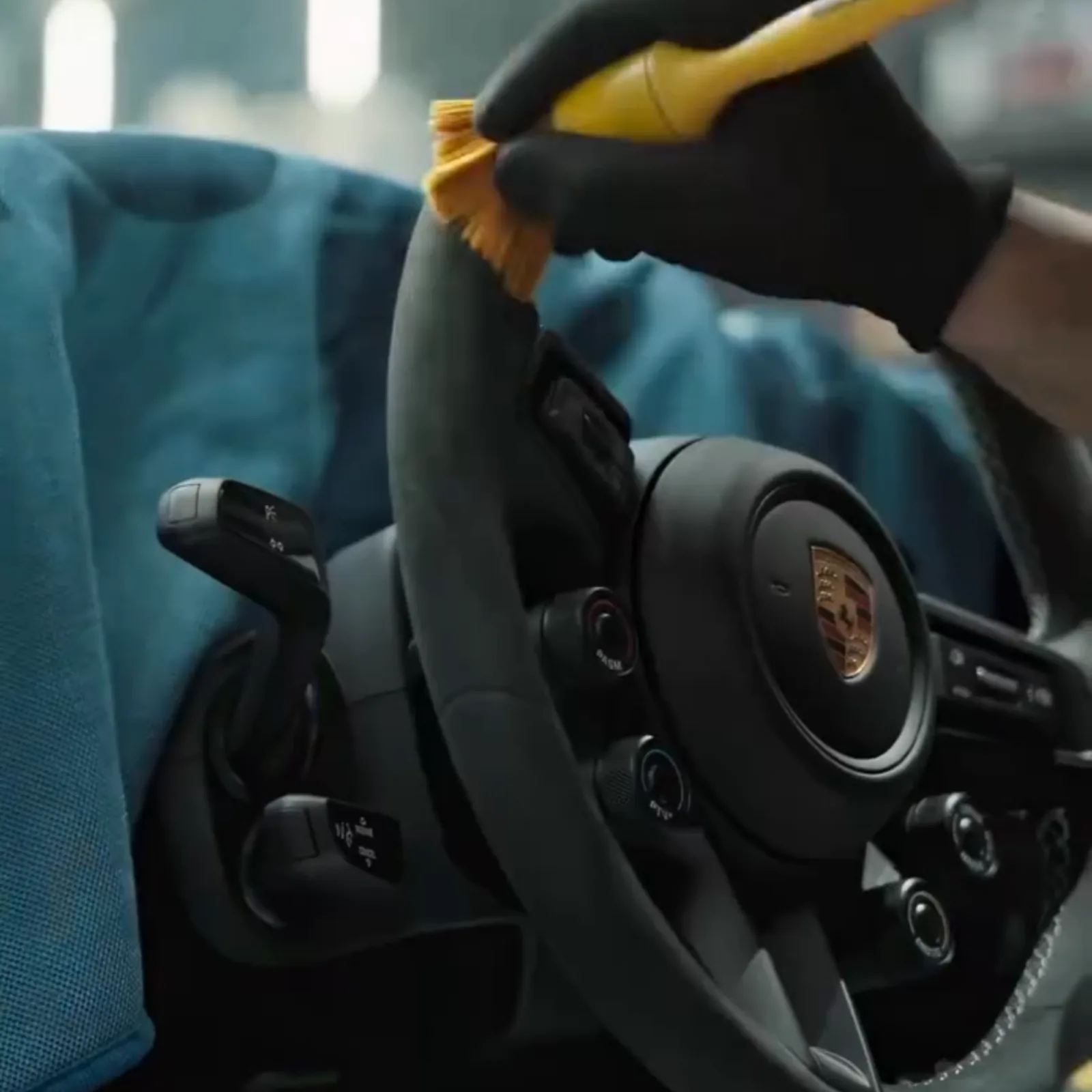 Detailing brush being worked across a Porsche steering wheel rim