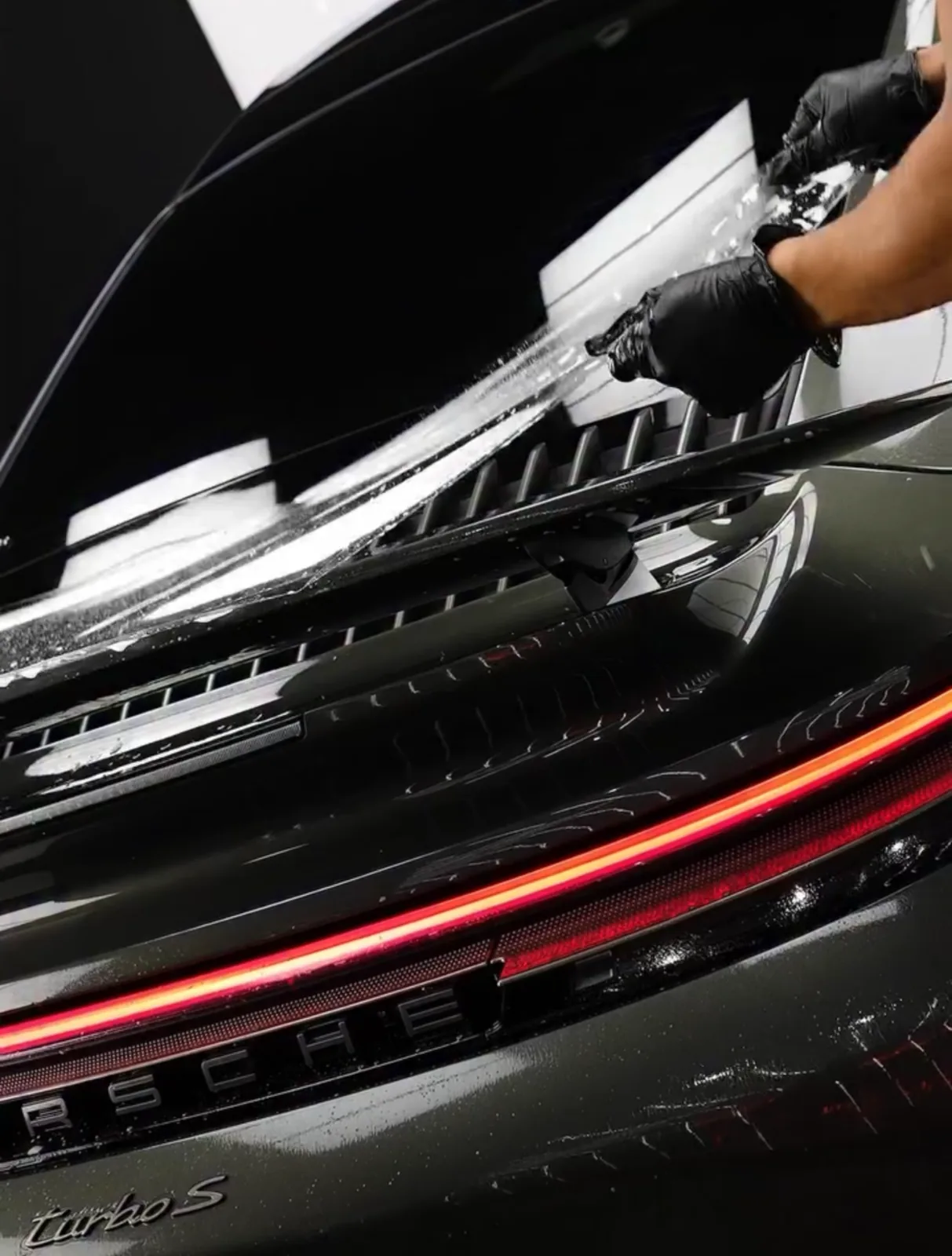 Paint protection film squeegeed across a Porsche engine lid and spoiler