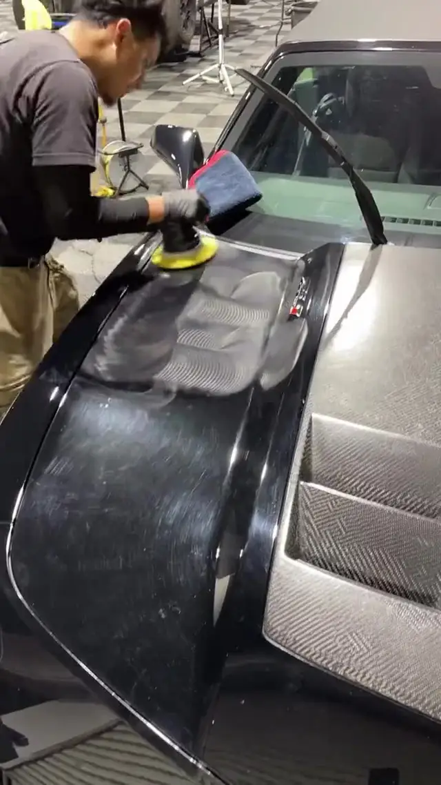 Machine polishing a black panel during paint correction